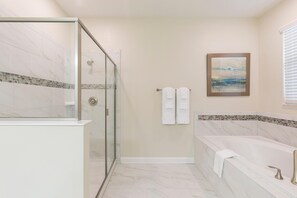 A modern bathroom with a glass shower enclosure, a bathtub, and a tiled floor. - 9069hs- The Retreat at Championsgate (Davenport)