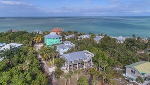 An aerial view of a coastal residential area with houses surrounded by dense tropical vegetation and a clear view of the ocean. - Near beach, includes golf cart , bikes , kayaks and pool , 5 stars. NCIC member (Captiva)