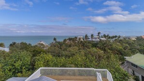 A coastal property with a wooden deck, lush greenery, and a view of the ocean. - Near beach, includes golf cart , bikes , kayaks and pool , 5 stars. NCIC member (Captiva)