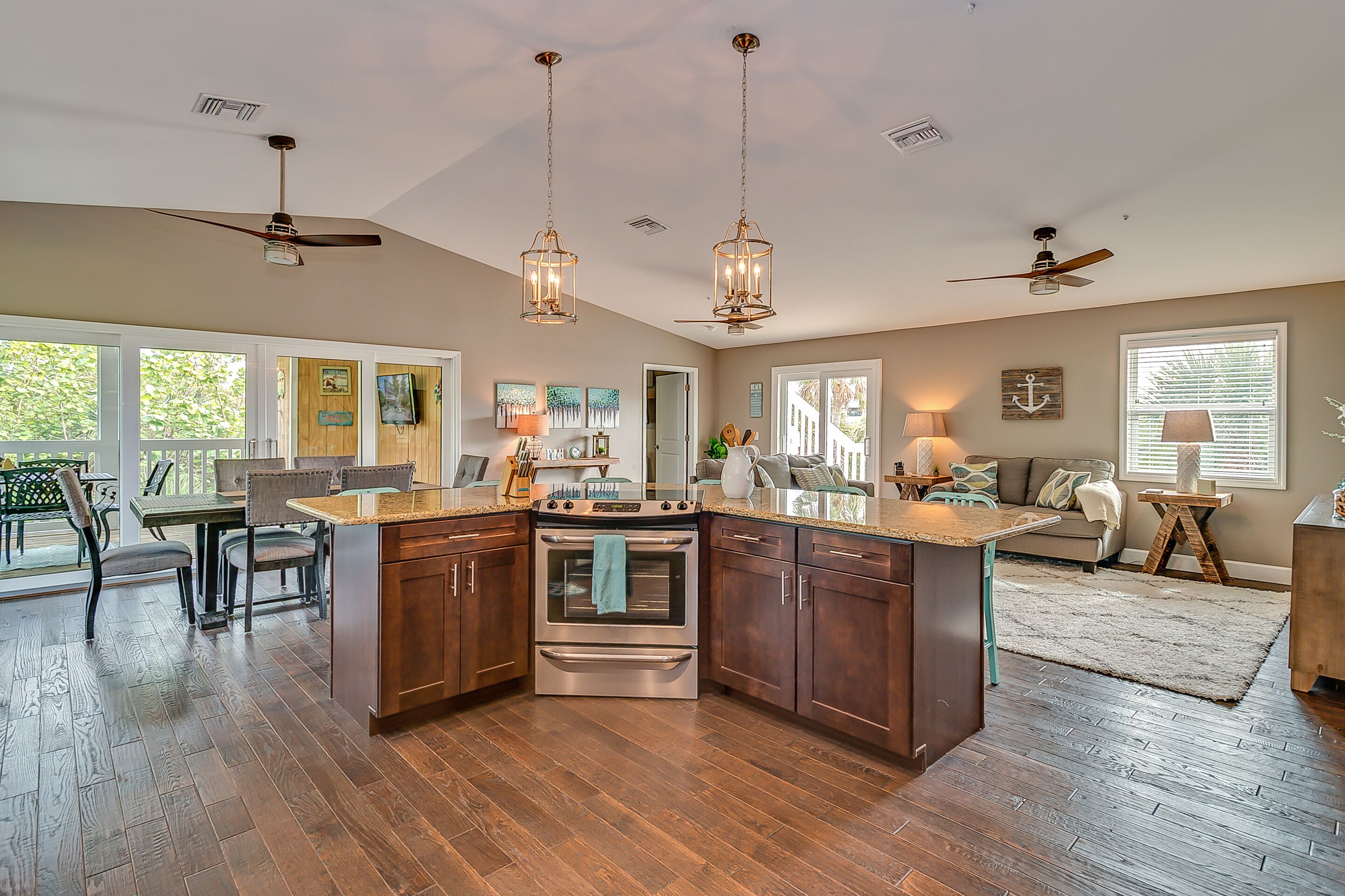 A spacious kitchen with a central island, wooden flooring, and pendant lighting.