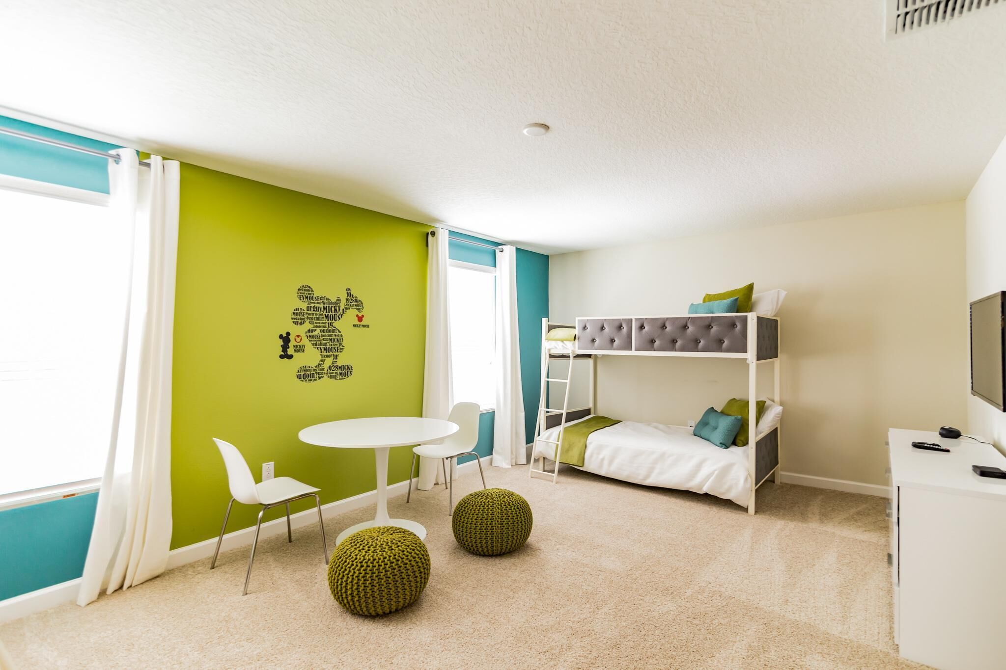A child's bedroom with a bunk bed, a desk, a chair, and a small table.