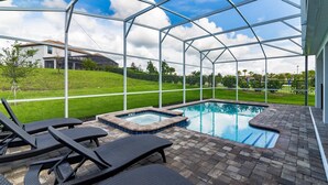 Une piscine extérieure avec des chaises longues, un jacuzzi et une vue sur une maison et un paysage verdoyant.