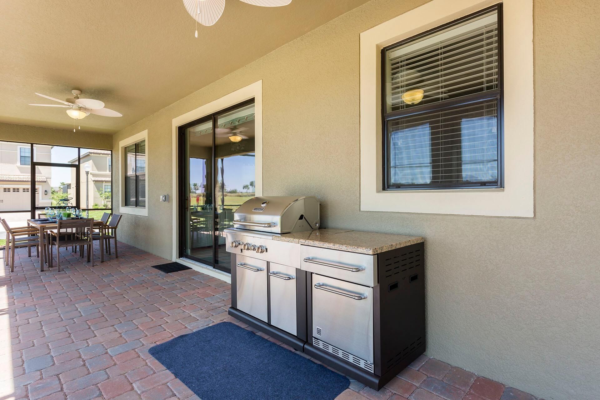 An outdoor patio with a grill, dining table, and chairs.