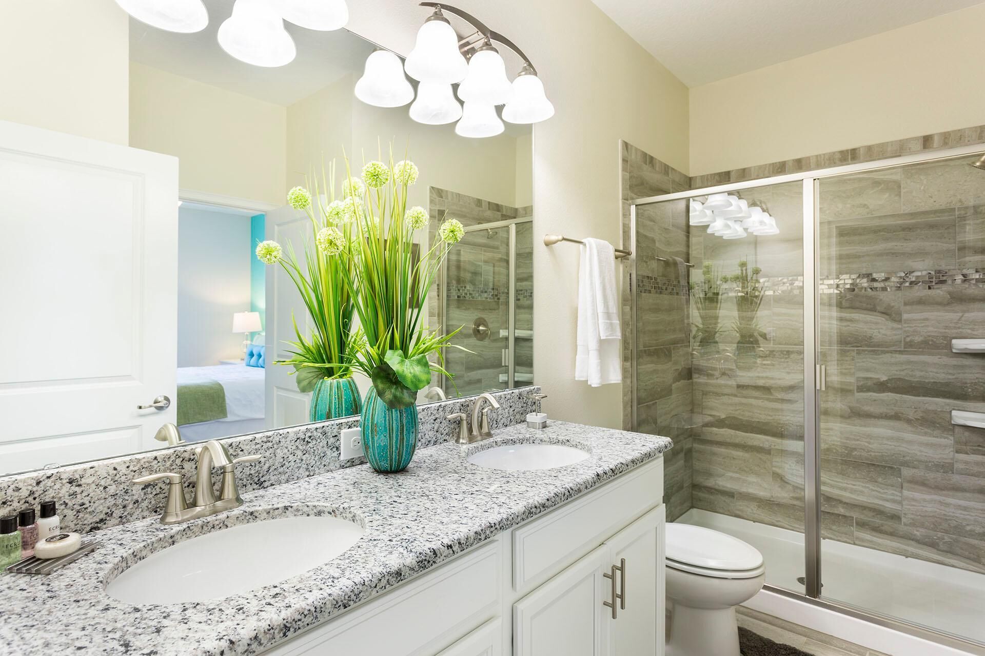 A bathroom with two sinks, a large mirror, and a glass shower enclosure.