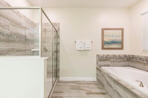 Et moderne badeværelse med brusekabine i glas, et fristående badekar og et flisebeklædt backsplash.