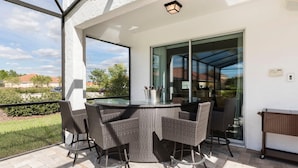 A covered patio with wicker furniture, a glass table, and a view of the surrounding area. - 4049otd-solterra Gated Resort (Davenport)
