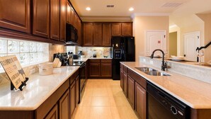 A kitchen with wooden cabinets, a black refrigerator, a sink, and a dishwasher. - 4049otd-solterra Gated Resort (Davenport)