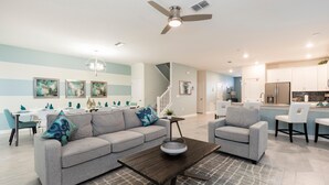 Ein geräumiges Wohnzimmer mit grauem Sofa, einem Couchtisch und einem Essbereich im Hintergrund.