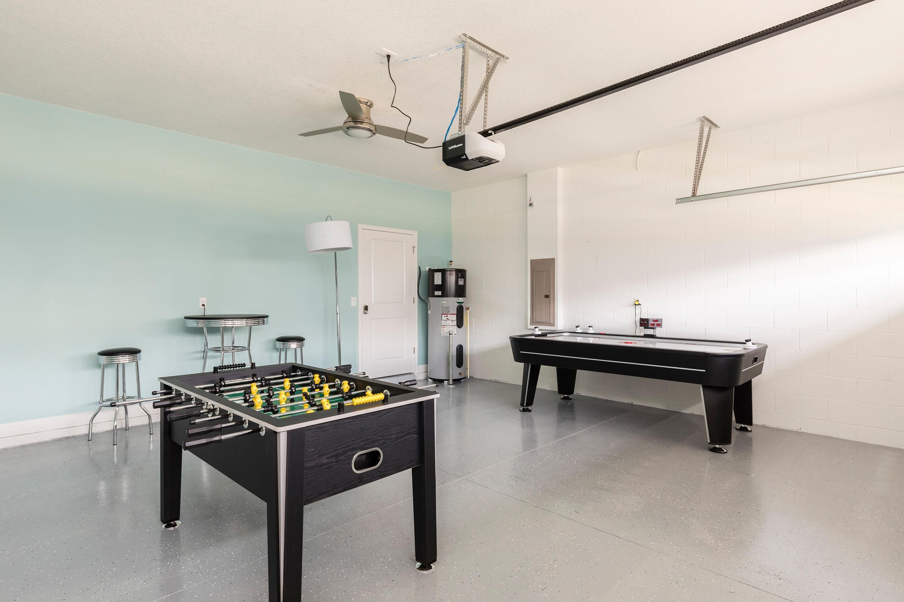 Une pièce équipée d’un baby-foot, d’une table de billard, d’un ventilateur de plafond et d’une lampe.
