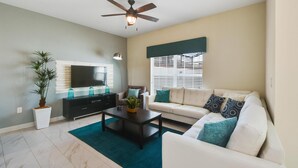 A living room with a sofa, coffee table, TV, and ceiling fan.