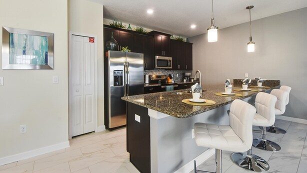A modern kitchen with a central island, stainless steel appliances, and bar seating.