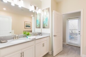 A bathroom with two sinks, a large mirror, and a door leading to another room.