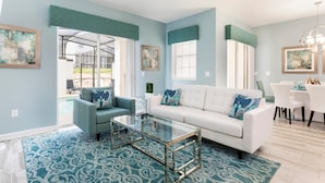 A spacious living room with a white sofa, two armchairs, a glass coffee table, and a dining area with a white table and chairs. - 9079dd-the Retreat at Championsgate (Davenport)