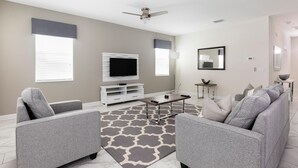 A modern living room with a grey sofa set, a flat-screen TV, a coffee table, and a patterned rug. - 1668mvd - Non-renting 6-12-2022 The Retreat at Championsgate (Davenport)