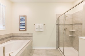 Une salle de bain équipée d’une baignoire, d’une douche et d’un espace de douche séparé par des parois en verre.