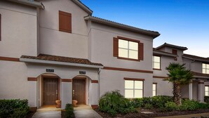 A two-story residential building with a beige exterior, brown trim, and a number "1577" above the entrance. - 1579mvd-the Retreat at Champions Gate (Davenport)