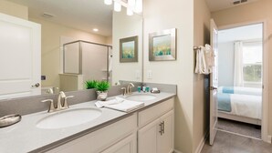 Une salle de bain avec deux lavabos, un grand miroir et une plante en pot.