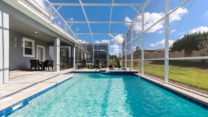 Une piscine dotée d’une structure en verre, d’un espace extérieur aménagé et offrant une vue sur les environs.