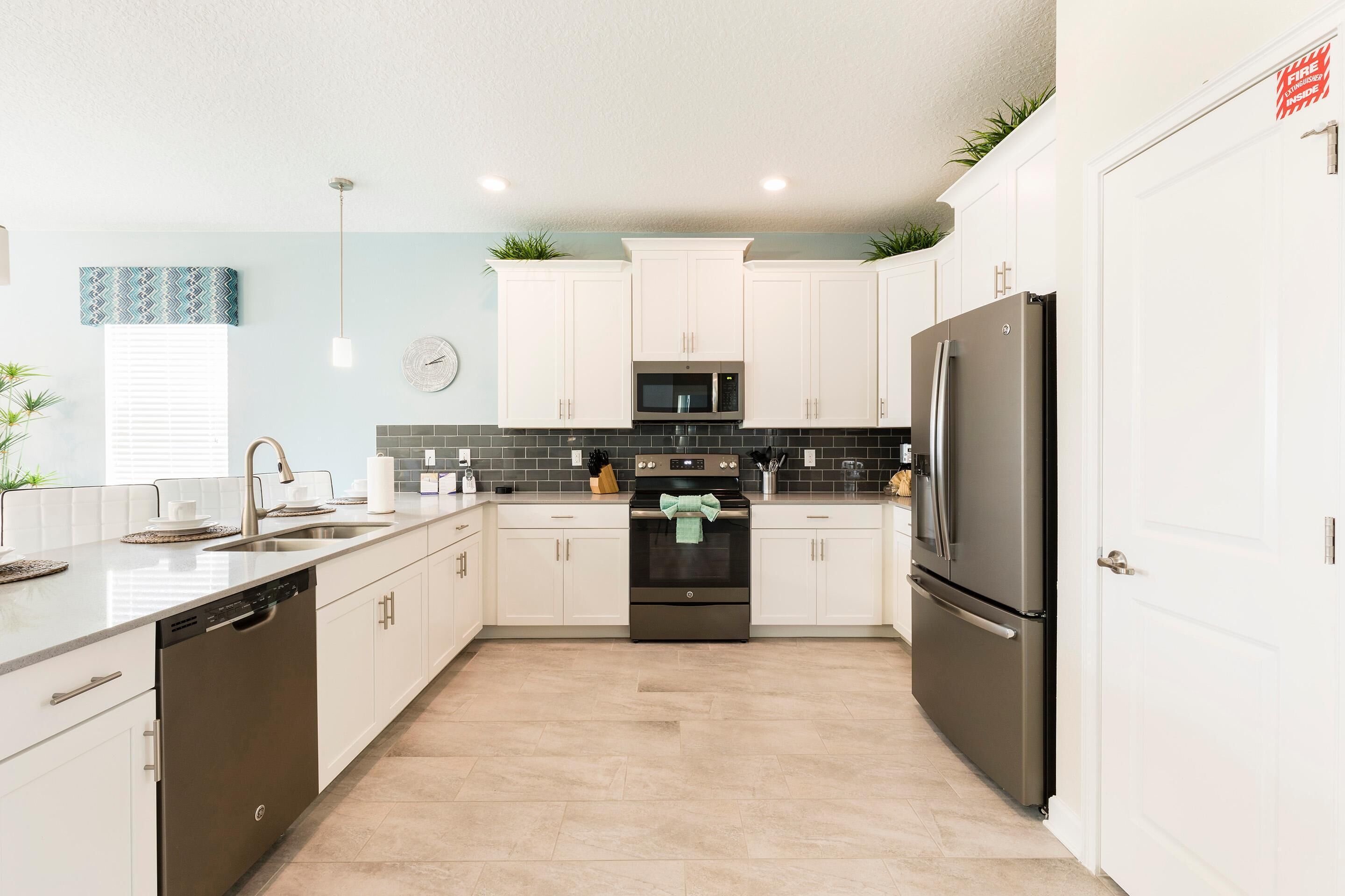 A modern kitchen with white cabinets, stainless steel appliances, and a tiled backsplash.