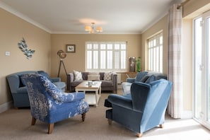 A living room with two blue armchairs, a sofa, a coffee table, and a floor lamp. - Sand Dollar: family-friendly holiday home in Rhosneigr (Rhosneigr)