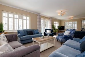 Relax in this stylish living room with a large window, flat-screen TV, and comfortable seating options.