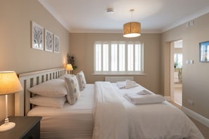 King-sized bed with quality linens and view to en-suite bathroom, first floor accommodation at luxury holiday home in Rhosneigr, Anglesey - Sand Dollar: family-friendly holiday home in Rhosneigr (Rhosneigr)