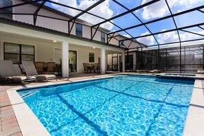 A swimming pool with lounge chairs and a covered patio area.