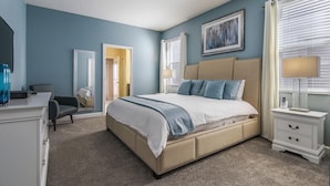 A bedroom with a large bed, bedside tables, a dresser, and a chair. - 1521fd - The Retreat at Championsgate (Davenport)