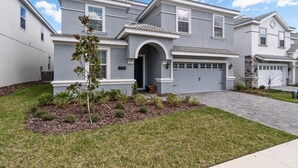 A two-story residential house with a grey facade, a central arched entrance, and a garage. - 1521fd - The Retreat at Championsgate (Davenport)