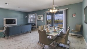 A dining area with a table set for six, a sofa, and a television in the background. - 1521fd - The Retreat at Championsgate (Davenport)