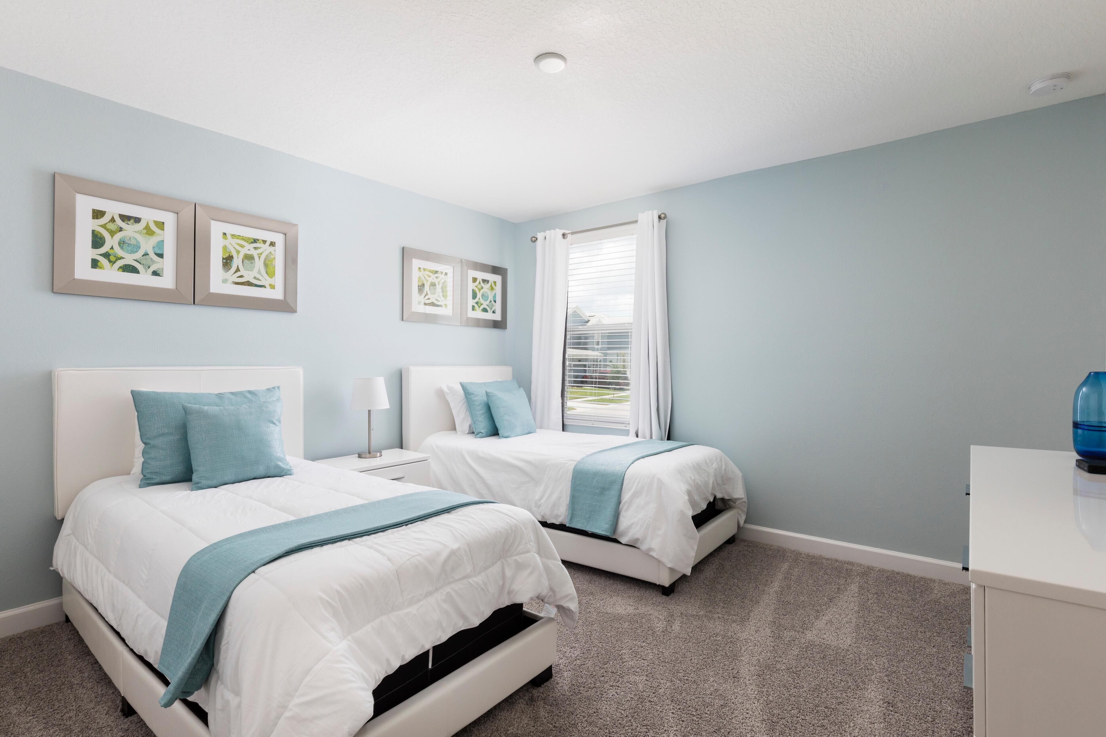 A bedroom with two beds, a nightstand, and a desk.