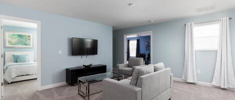 A living room with a grey sofa, a coffee table, a flat-screen TV, and a TV stand.