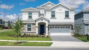 Kaksikerroksinen talo, jossa on kiviverhous, sininen pääovi ja autotalli.