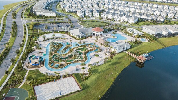 Ett flygbildsbild av ett bostadsområde med ett poolområde, en basketplan och en småbåtshamn.
