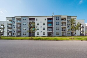 A multi-story residential building with balconies, a flagpole, and a well-maintained lawn. - 4741ctd- Storey Lake (Kissimmee)