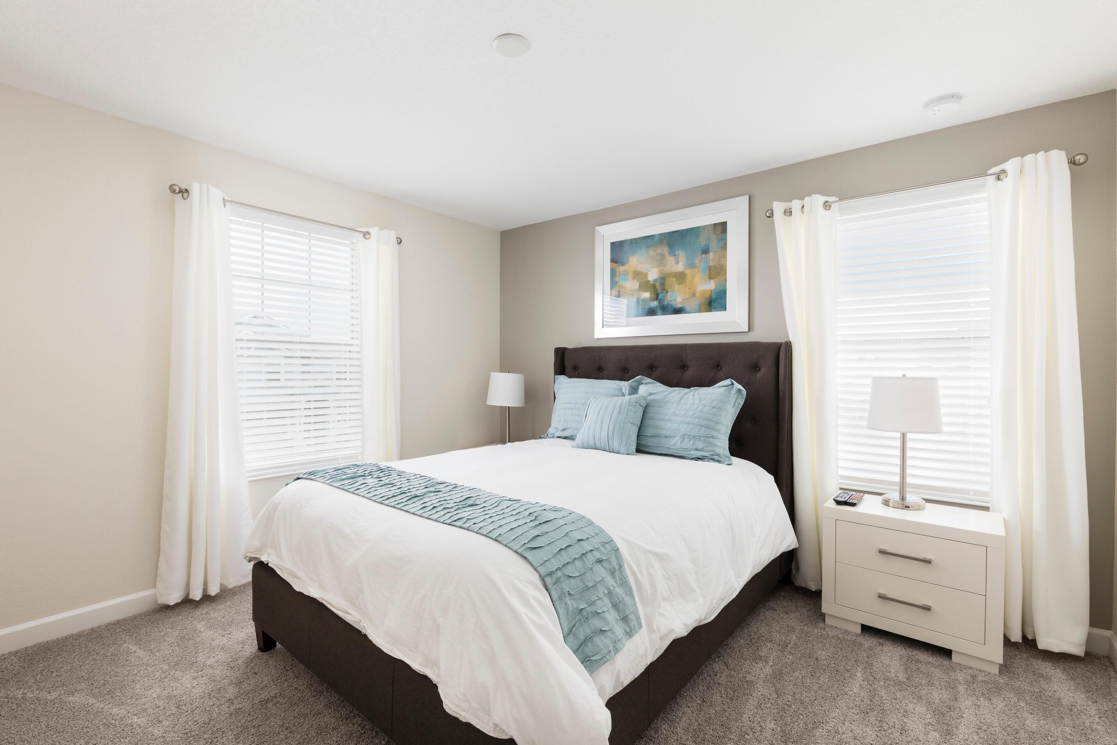 A bedroom with a bed, nightstands, a lamp, and a painting on the wall.