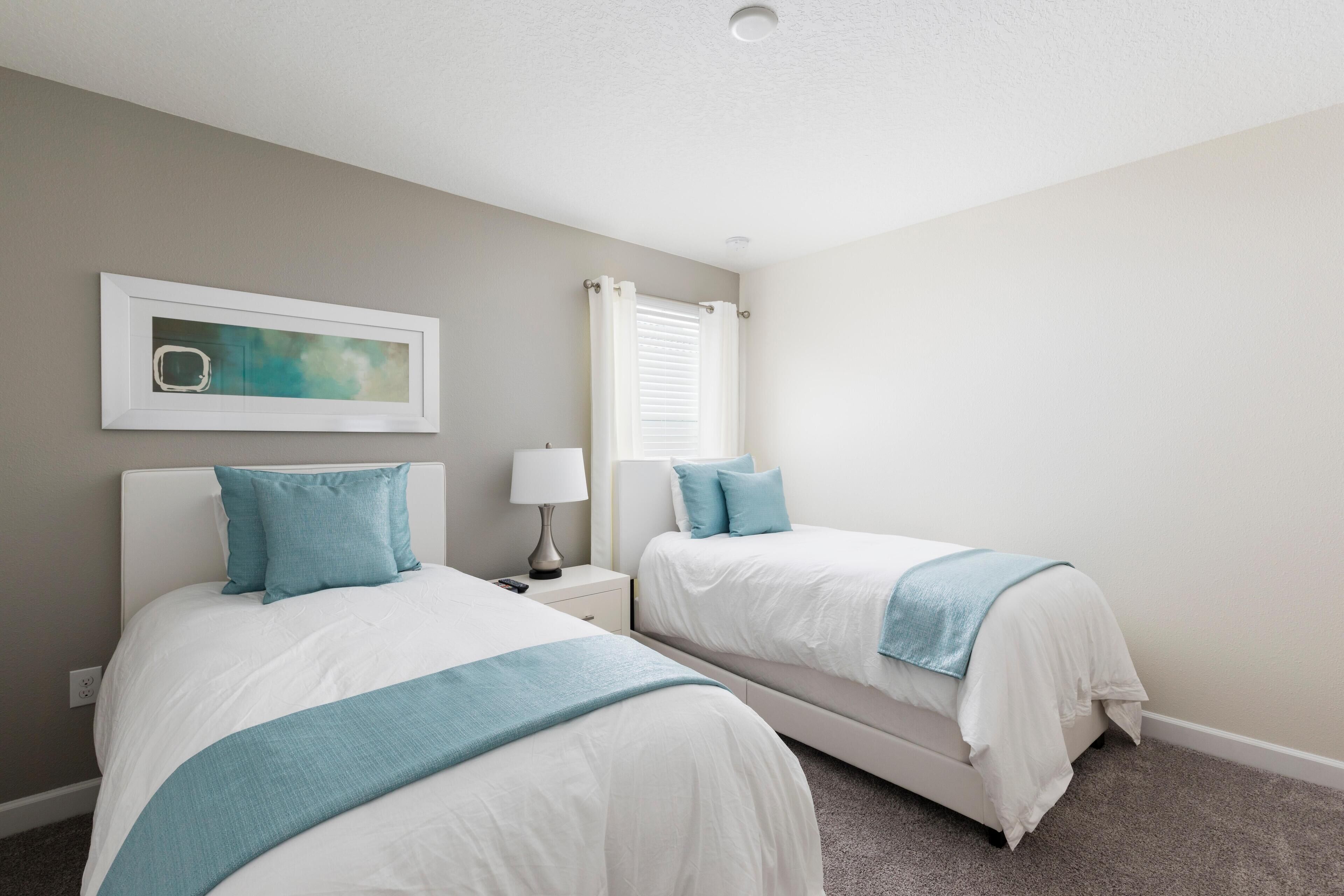 A bedroom with two beds, a nightstand, a lamp, and a framed picture on the wall.