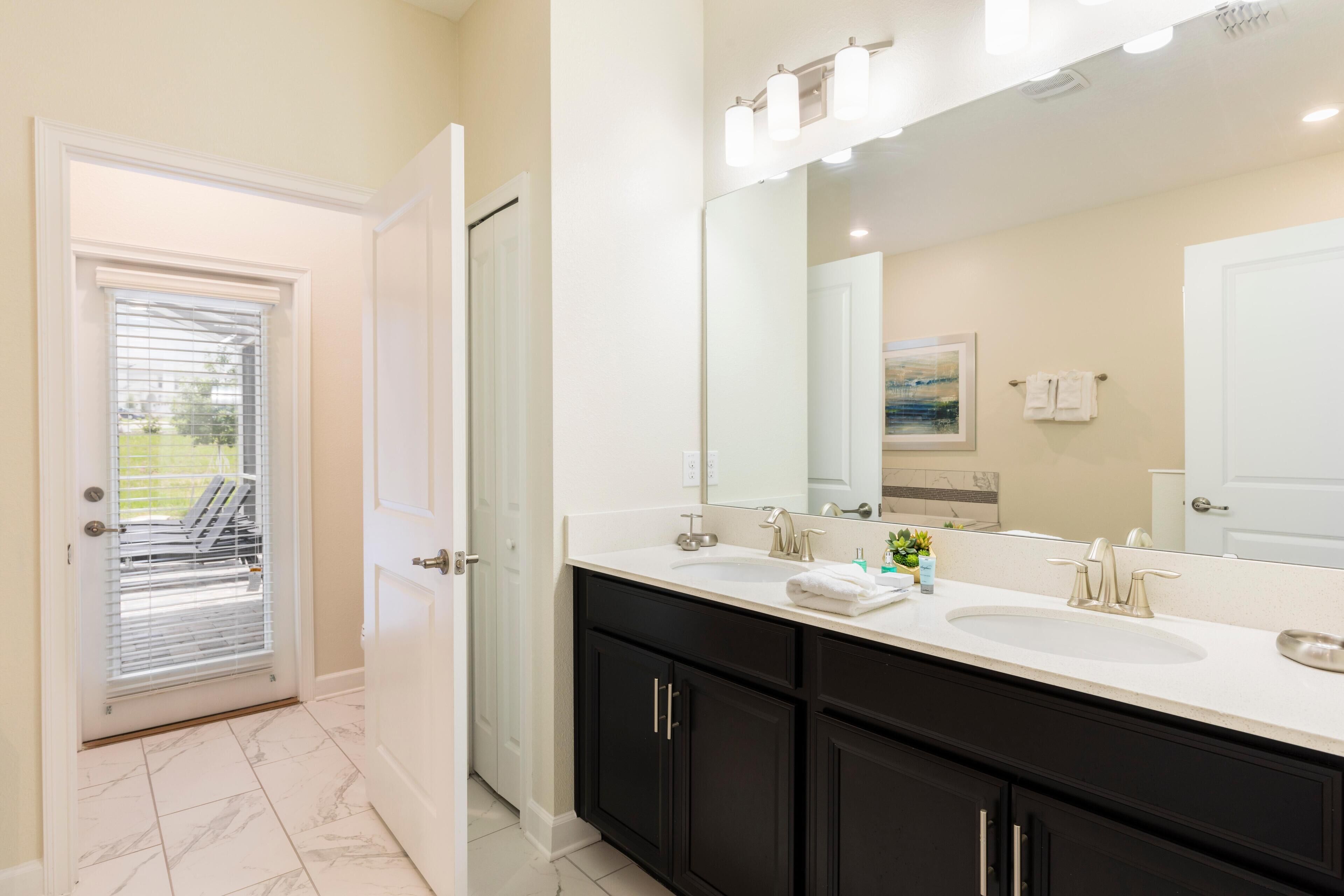 A bathroom with a double sink, dark cabinets, and a large mirror.