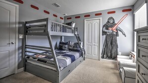 Une chambre avec un lit superposé, un luminaire au plafond, une armoire et une fresque représentant un chevalier.