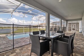 Relax by the pool with a clear view of the surrounding landscape, surrounded by a glass-enclosed patio with a table and comfortable seating.
