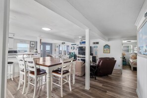 Un vaste espace de vie comprenant une table à manger, des chaises et un coin salon avec un canapé et un fauteuil.