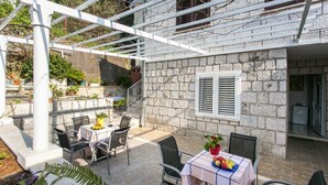 Un edificio de piedra con un patio cubierto, mobiliario exterior y una estructura de pérgola.