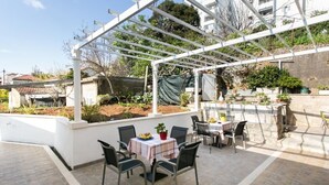 An outdoor patio area with a pergola, a table with chairs, and potted plants. - Guest House Kusalo- Basic Triple Room with Patio (Dubrovnik)