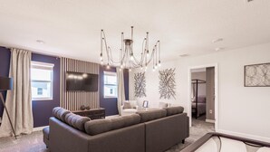 A modern living room with a sectional sofa, a chandelier, and abstract wall art.