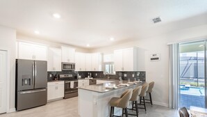 A modern kitchen with white cabinets, stainless steel appliances, and a large island with bar stools.