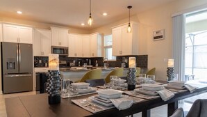 A modern kitchen with white cabinets, stainless steel appliances, and a dining area set for four.