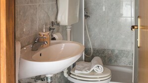 Et badeværelse med toilet, håndvask og bruser.