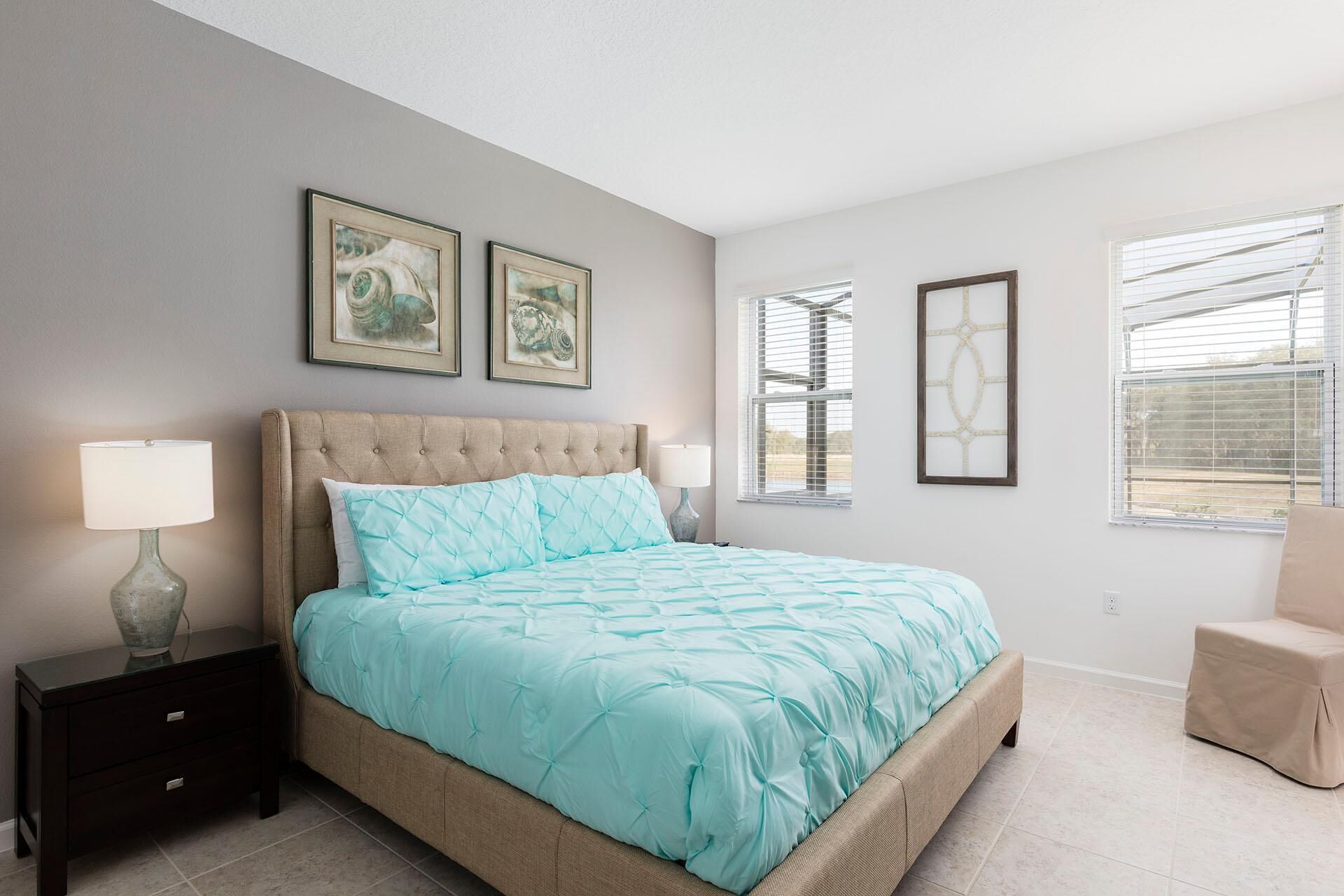 A bedroom with a bed, two bedside tables, a nightstand, and a window with blinds.