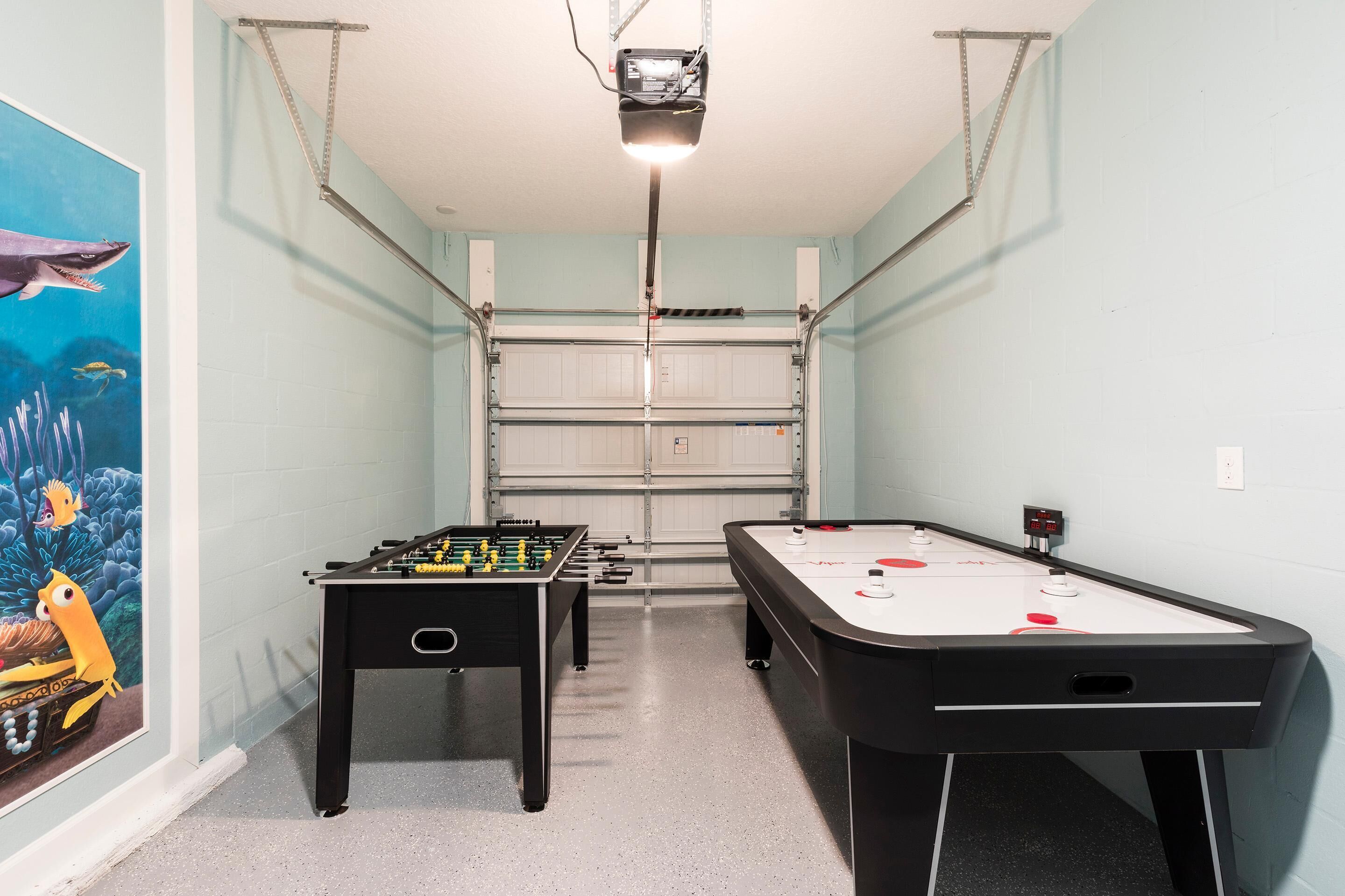 Ett rum med ett fotbollsspel, ett biljardbord och en projektor som är monterad i taket.