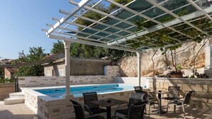 Un espace extérieur avec une piscine, une pergola, des marches en pierre et des sièges.